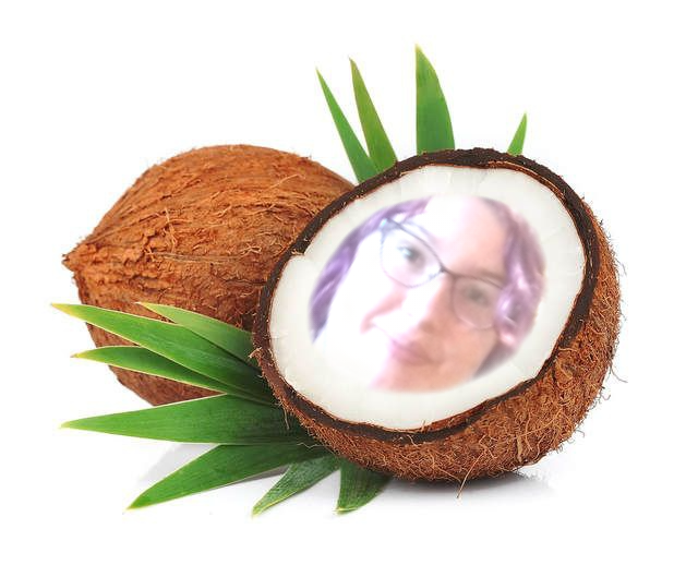 Half of a coconut sits against a whole coconut. Inside the flesh of the coconut, there is a face. They are white and feminine with purple hair, brown eyes, and glasses. The face seems to be glowing somewhat.